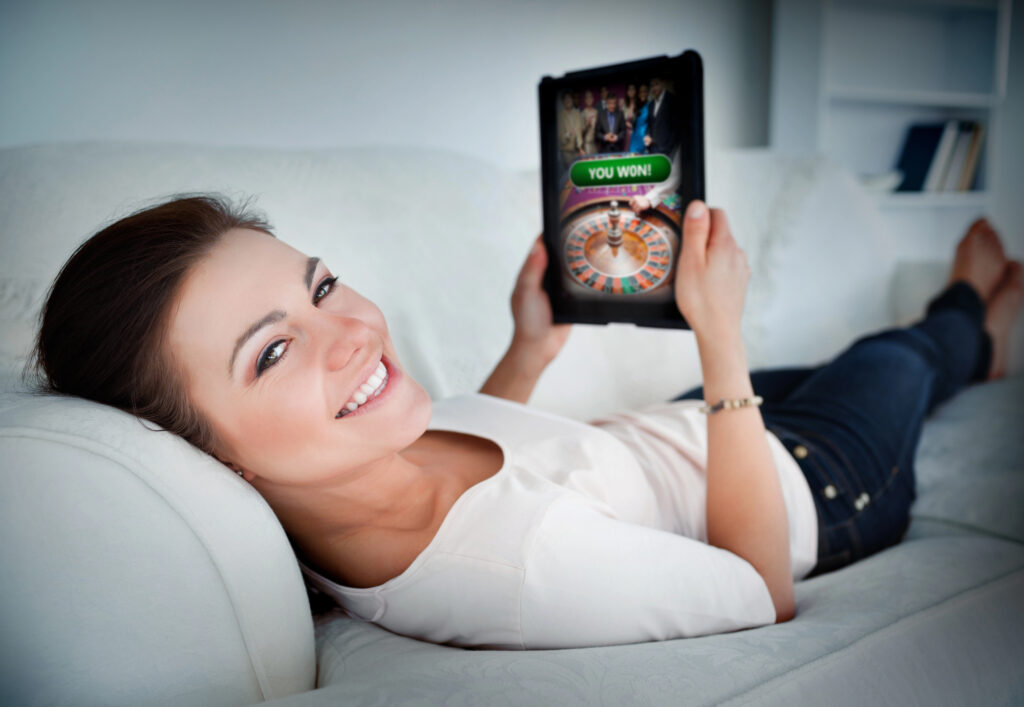 Woman relaxing on couch while gambling on tablet device