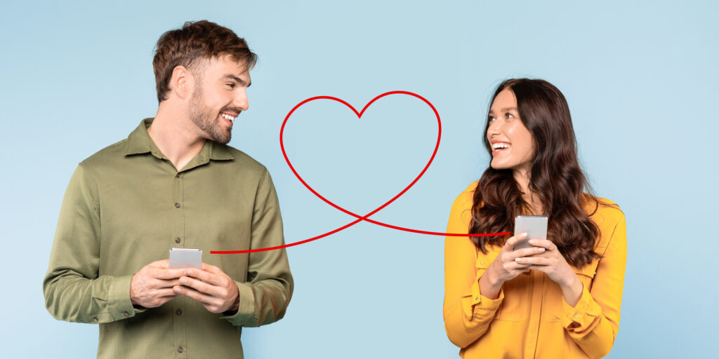 Two people using smartphones connected by heart symbol