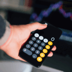 Hand holding smartphone calculator app with number pad display